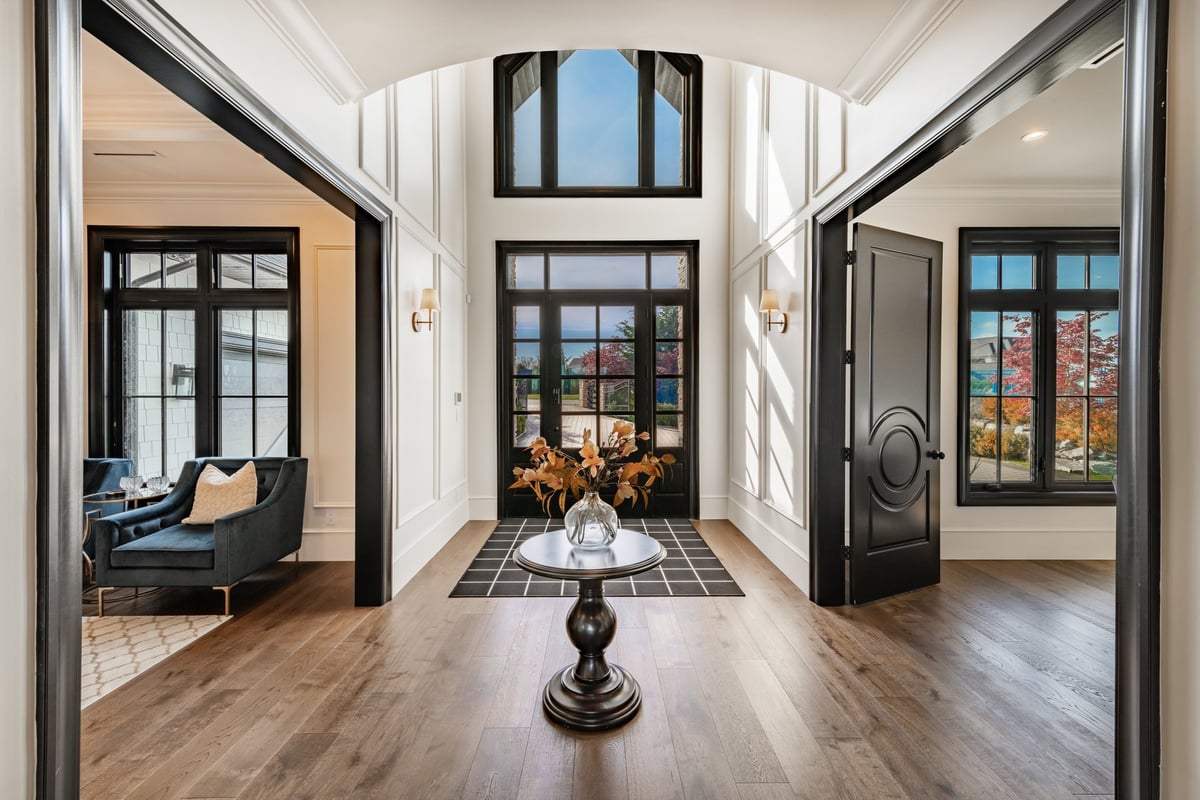 Grand entry foyer with a tall black-framed glass door and wood accents